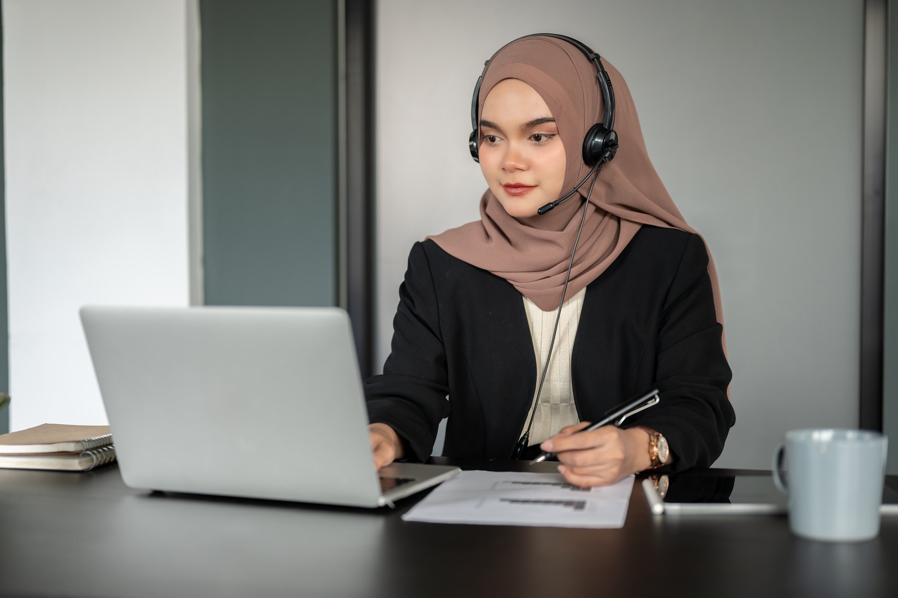 A confident Asian Muslim female call centre operator is working in the call centre office.